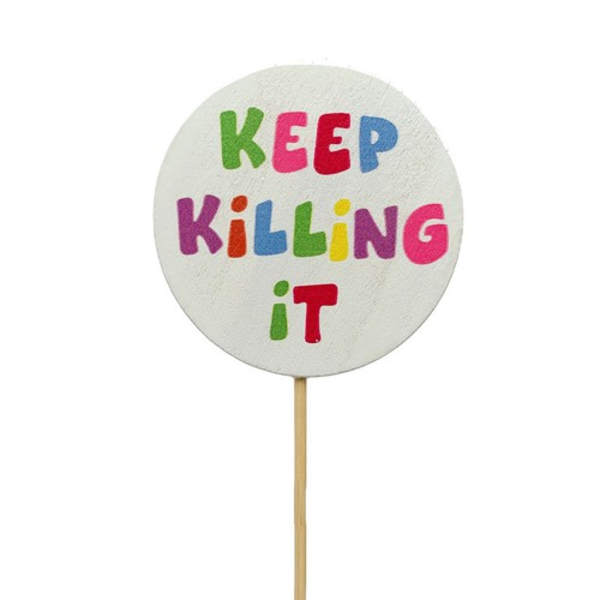 Round white sign on a stick with colorful text reading "KEEP KILLING IT"