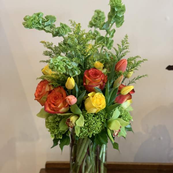 Mixed bouquet of orange and yellow roses in a clear glass vase