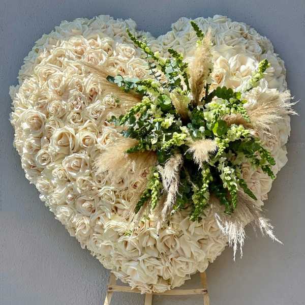 Heart-shaped cream rose floral display with greenery and pampas grass