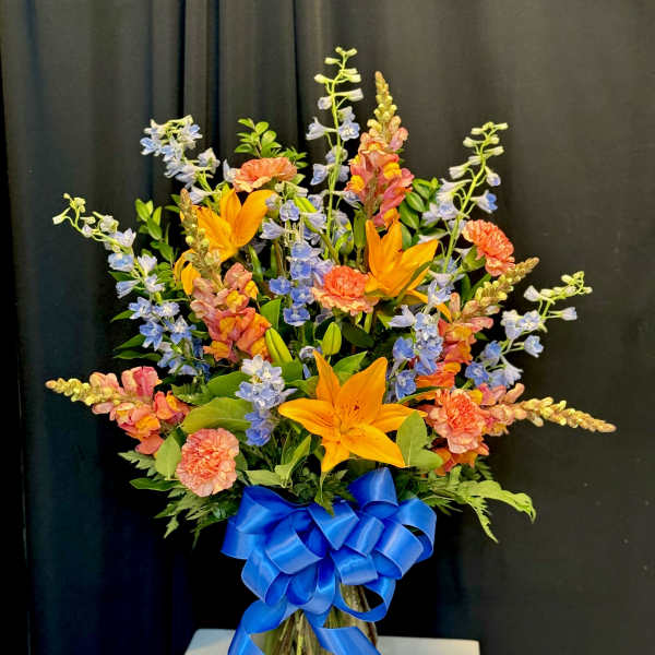 Colorful mixed bouquet in a glass vase with a blue ribbon