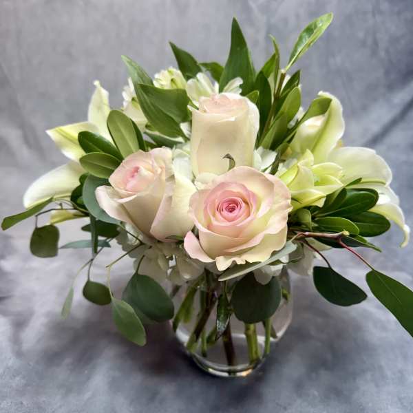 Pink roses and white lilies arranged in a clear glass vase