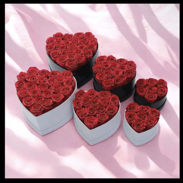Heart-shaped boxes filled with red roses on a pink background