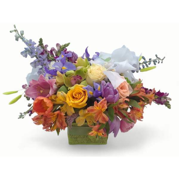 Low green basket filled with bright orange, yellow, purple, pink, and white mixed flowers.