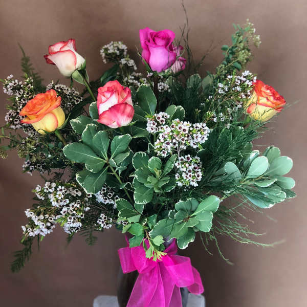 Bouquet of multicolored roses in a black vase with a pink ribbon