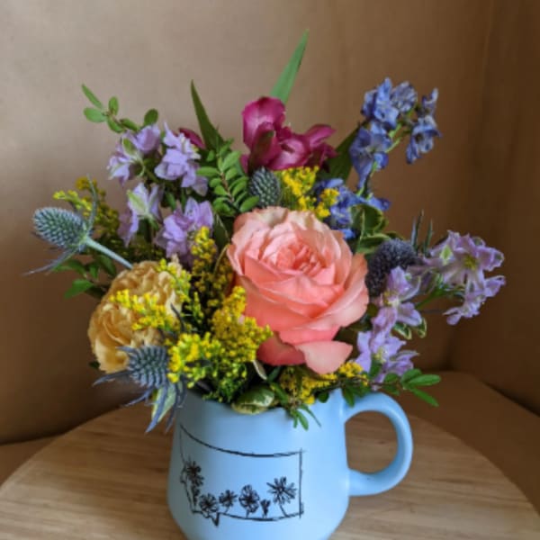 Mixed bouquet in a light blue mug-style vase