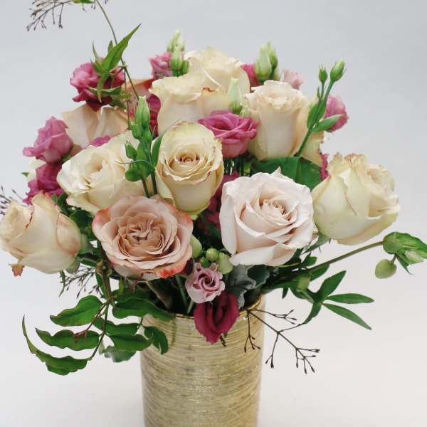 Bouquet of cream and pink roses in a gold vase