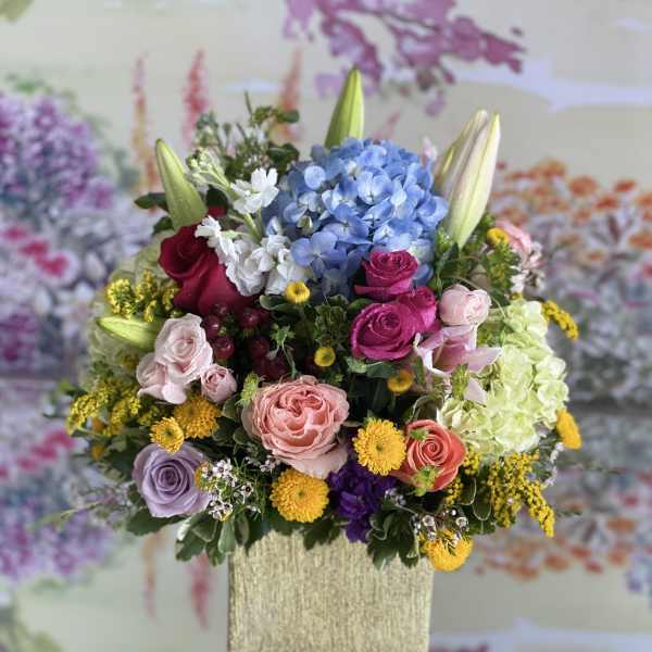 Colorful mixed flower arrangement in a tall square vase