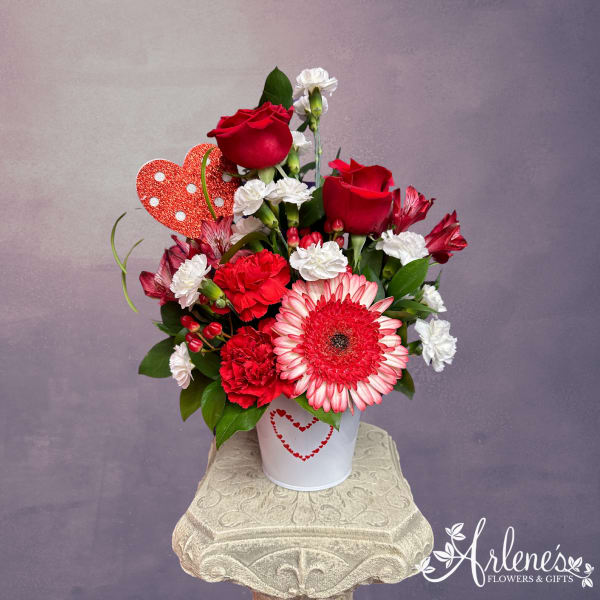 Red and white flower arrangement in a white tin with a heart decoration