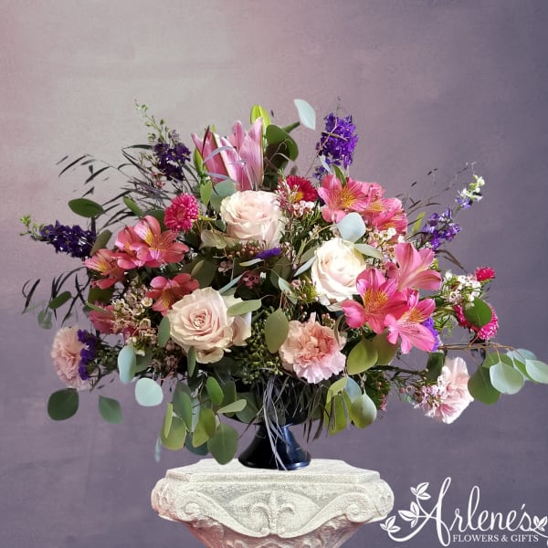 Pink and white floral arrangement in a black vase