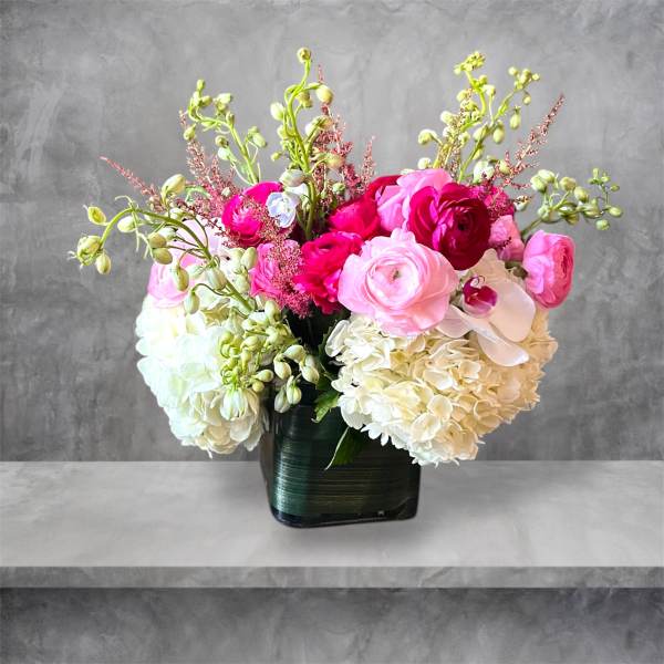 Pink and white floral arrangement in a dark square vase