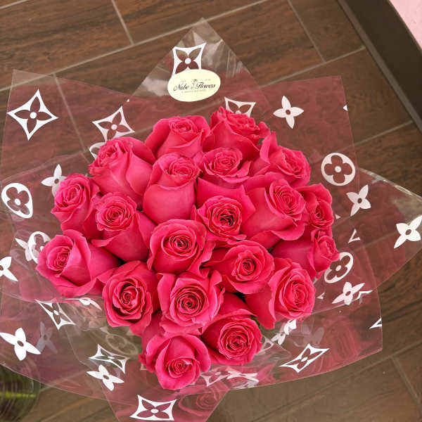 Bouquet of hot pink roses wrapped in clear cellophane with a white patterned design