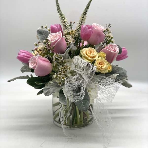 Pink and yellow roses with tulips in a glass vase