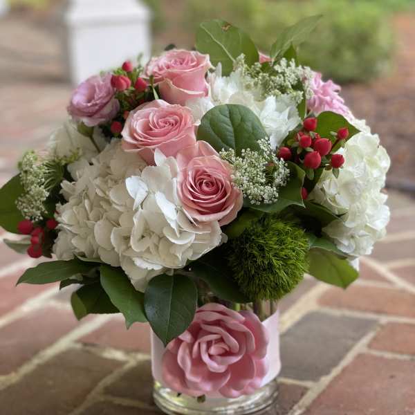 Pink roses and white hydrangeas in a glass vase with greenery