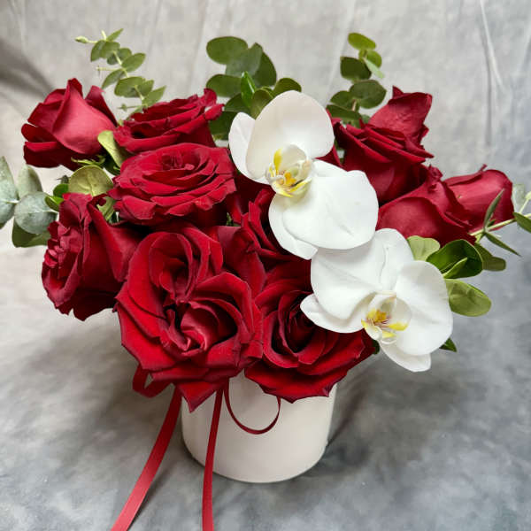 Red roses and white orchids arranged in a white vase