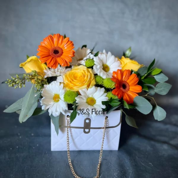Bouquet of orange and yellow flowers in a white handbag-style box