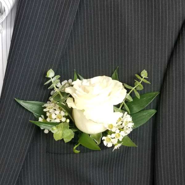 White rose boutonniere with small white filler flowers and greenery