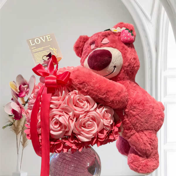 Pink teddy bear hugging a bouquet of pink roses in a glass vase