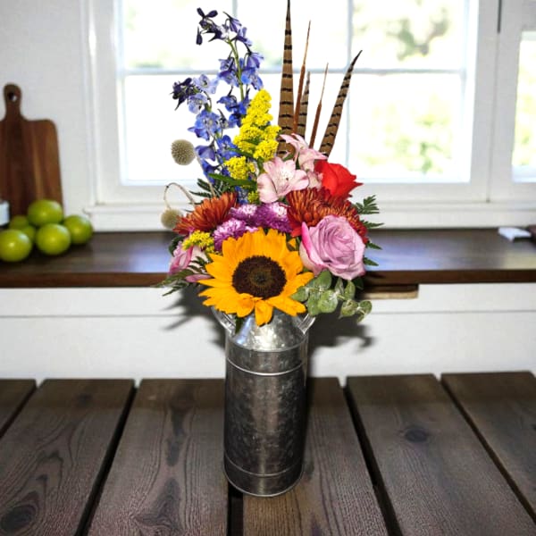 Mixed bouquet with a sunflower, roses, and blue flowers in a metal vase