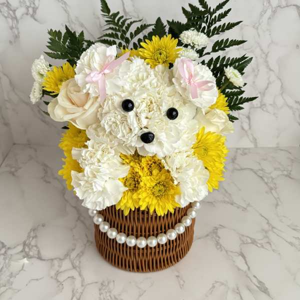 White and yellow flower arrangement in a wicker basket with a pearl trim