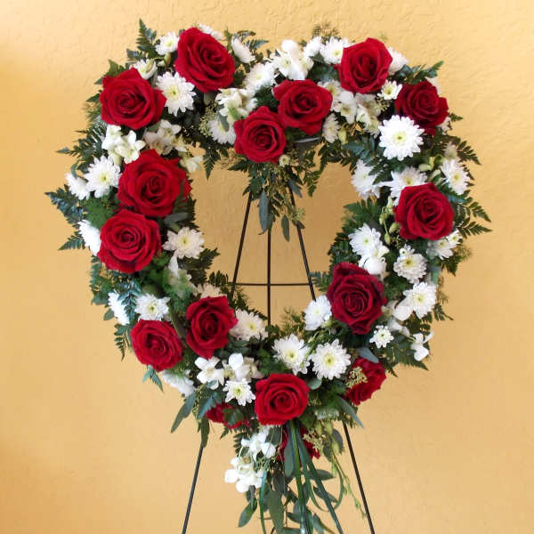 Heart-shaped wreath of red roses and white daisies on a stand