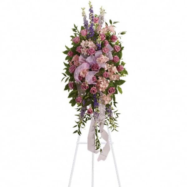 Standing floral spray with pink and purple flowers on a white easel