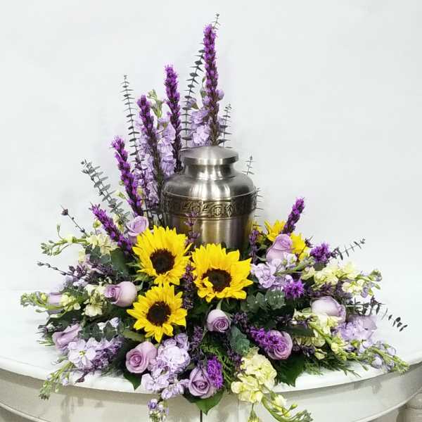 Purple and yellow floral arrangement around a silver urn