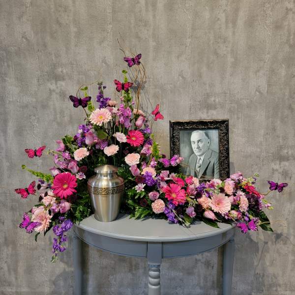 Pink and purple floral arrangement with a silver urn and framed portrait