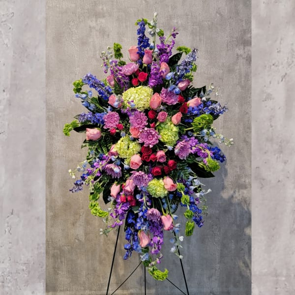 Tall standing floral spray with pink roses, purple blooms, and green hydrangeas