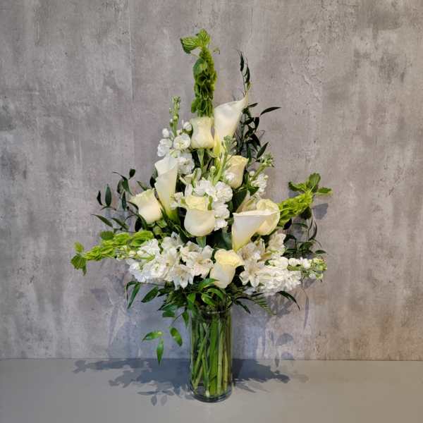 Tall white floral arrangement in a clear glass vase
