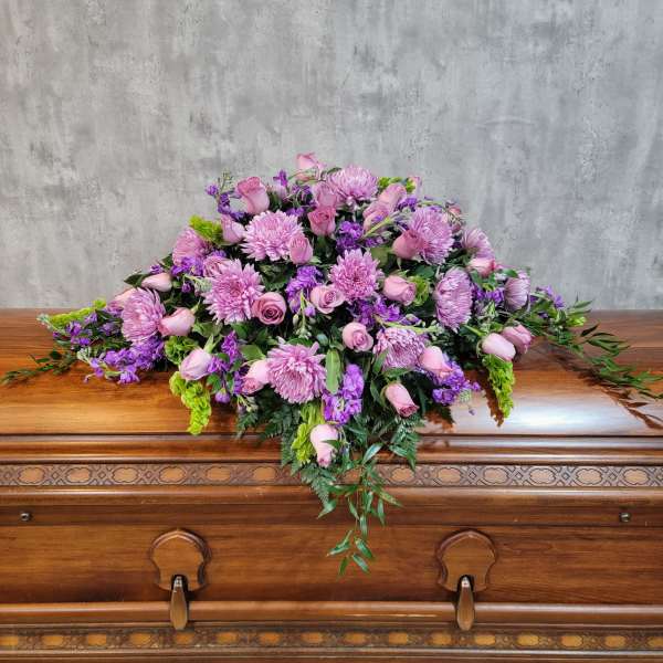 Pink and purple floral casket spray with roses and chrysanthemums