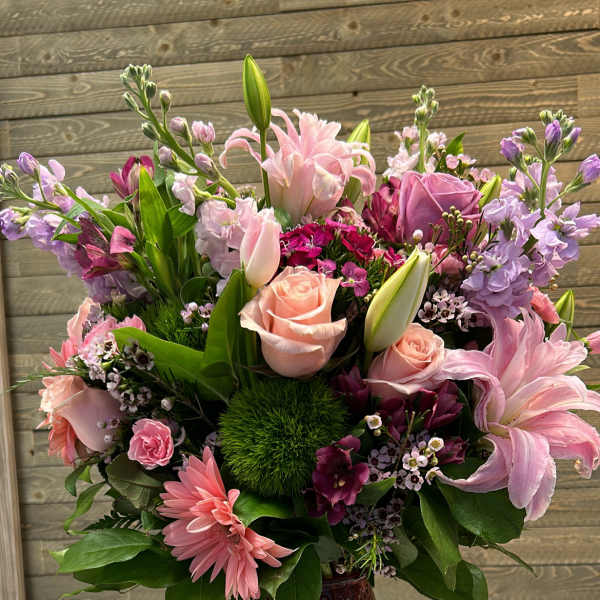 Pink and lavender mixed flower arrangement in a textured vase