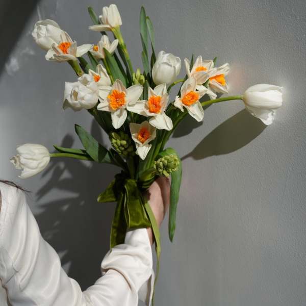 Handheld bouquet of white daffodils with orange centers and white tulips