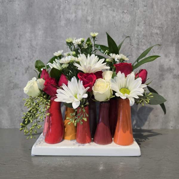 Bouquet of red and white roses with white daisies in colorful small vases