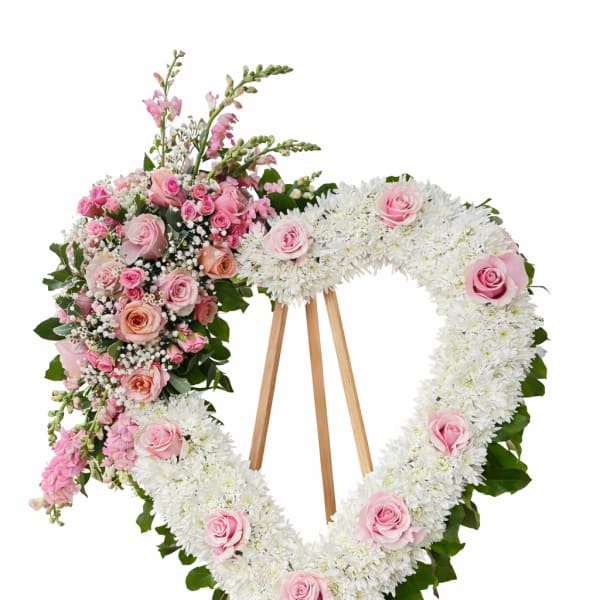 Heart-shaped standing wreath of white flowers and pink roses on a wooden easel
