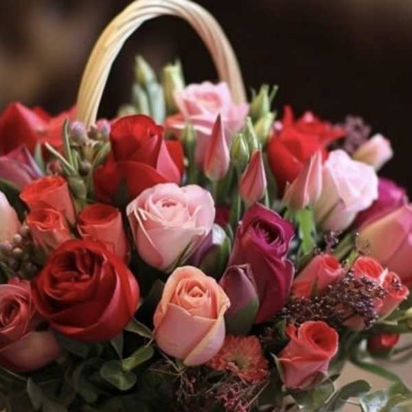 Basket of mixed roses and tulips in pink and red tones