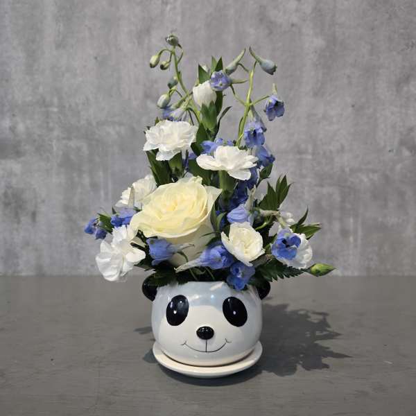 White and blue flowers arranged in a panda-face ceramic pot