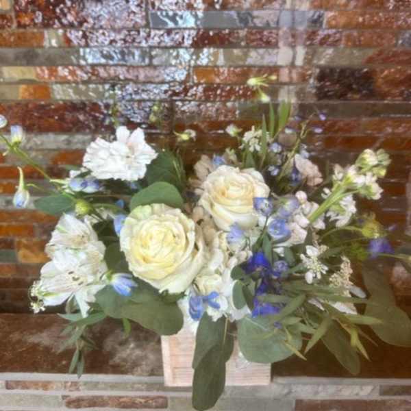 Bouquet of white roses and blue-white flowers in a wooden box