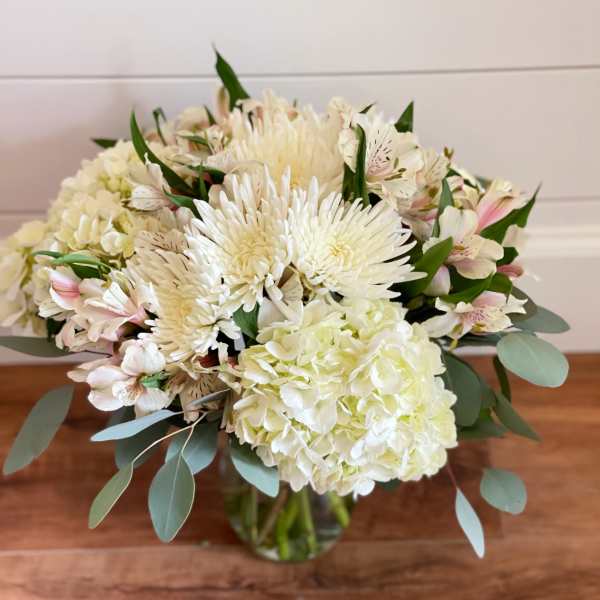 White bouquet with hydrangea, chrysanthemums, and pale pink alstroemeria in a glass vase
