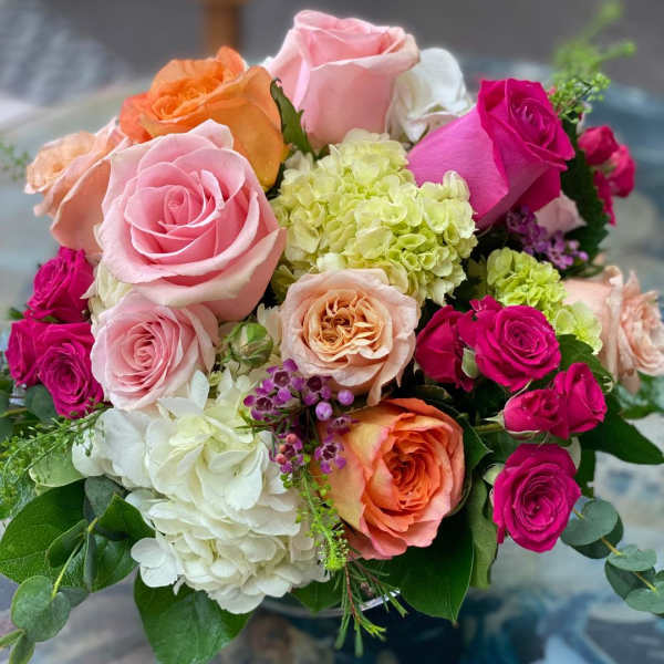 Bouquet of pink, orange, and white roses with pale hydrangeas