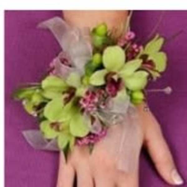 Green orchid wrist corsage with pink accents on a hand