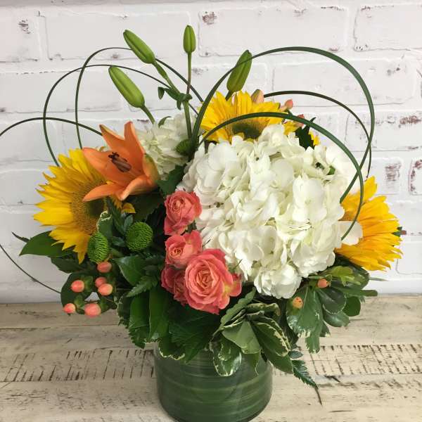 Bouquet of sunflowers, white hydrangea, pink roses, and orange lilies in a green vase