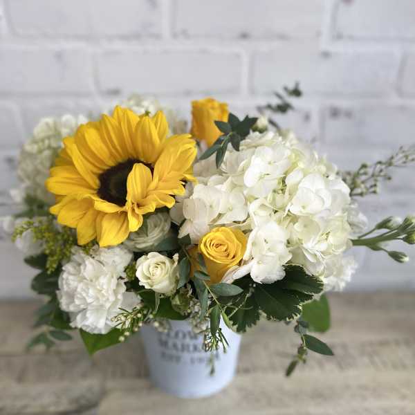 Sunflower and white hydrangea bouquet in a white container