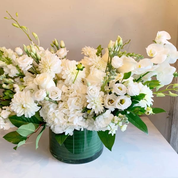 White floral arrangement in a green glass vase