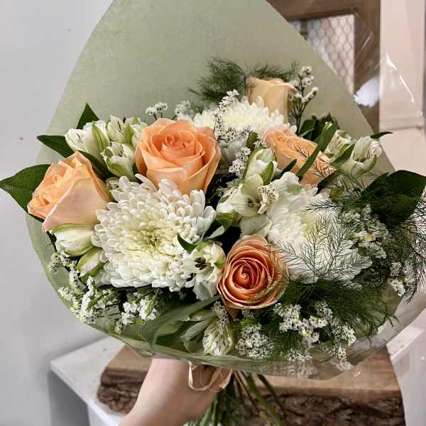 Peach roses and white chrysanthemums in a wrapped bouquet
