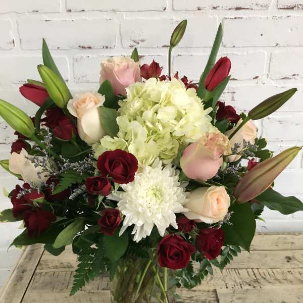 Bouquet of red and blush roses with white hydrangea in a glass vase