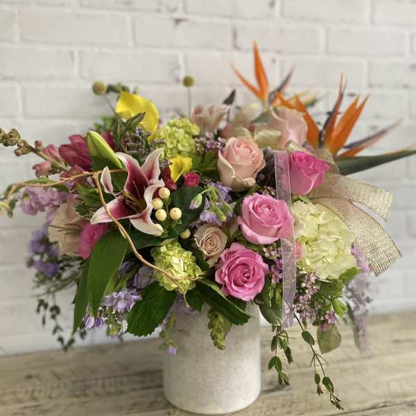 Mixed bouquet of pink roses, lilies, and hydrangeas in a white vase
