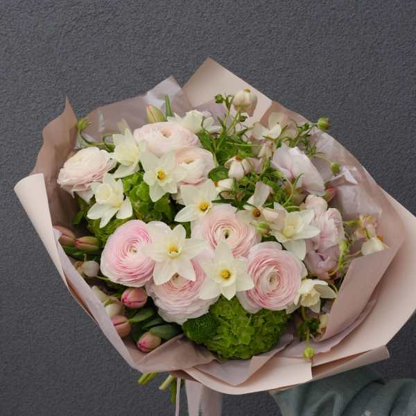 Hand-tied bouquet of pale pink and white flowers wrapped in blush paper