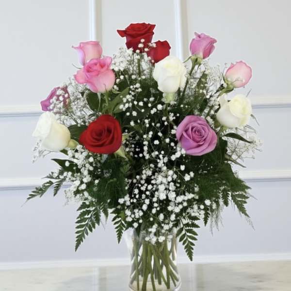 Bouquet of red, pink, purple, and white roses in a clear glass vase