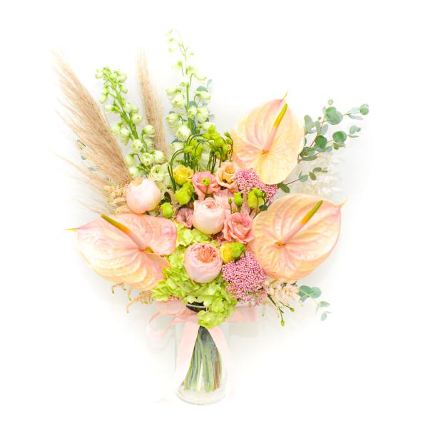 Pastel bouquet with anthuriums, roses, and tall green spikes in a glass vase