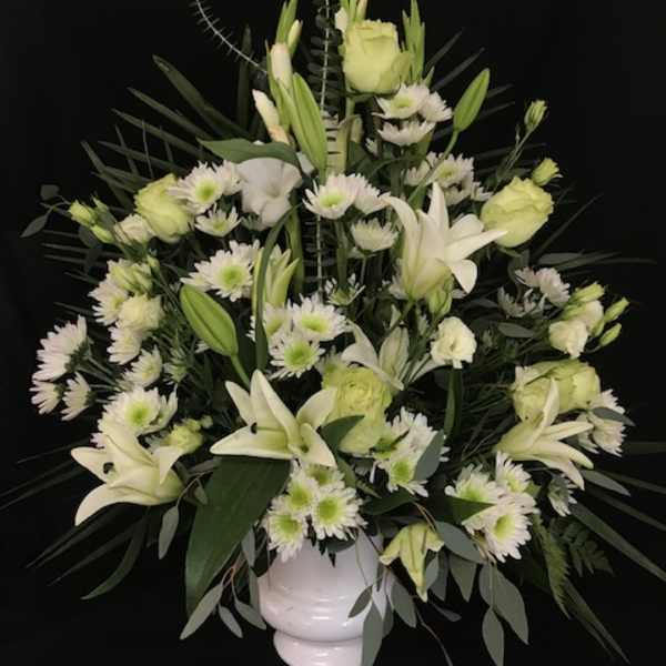 White lilies and daisies arranged in a white vase